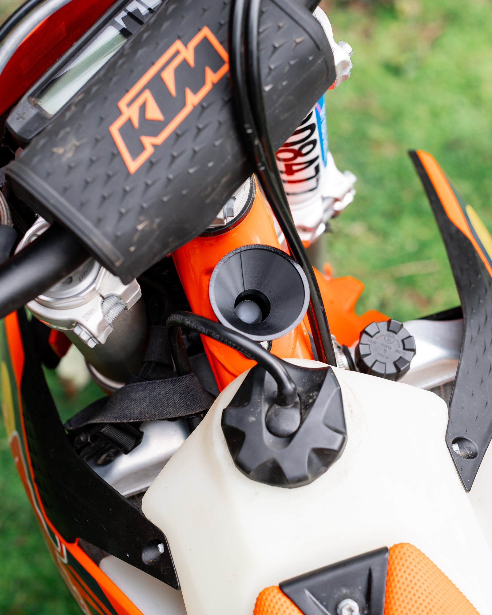 Close-up of a KTM motorcycle 2-stroke oil filler with a DIRT-EH 2-stroke oil funnel