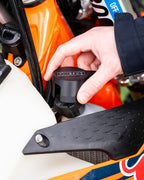 Close-up of a KTM motorcycle radiator with a DIRT-EH radiator cap removal tool